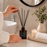 Difusor ambiental BEKOKO con varillas y aroma a sándalo y ámbar, 150ml, en frasco elegante para decorar y perfumar espacios.