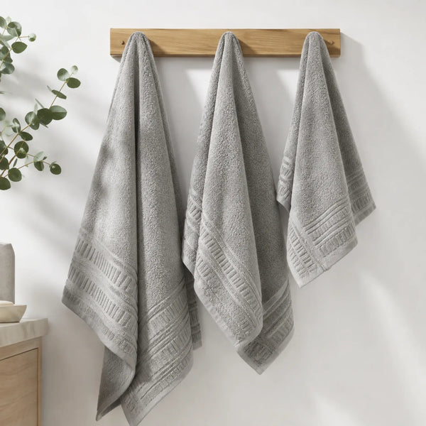 Juego de 3 toallas de baño en algodón premium de 700 GSM, suaves y absorbentes, en color blanco con borde gris claro.