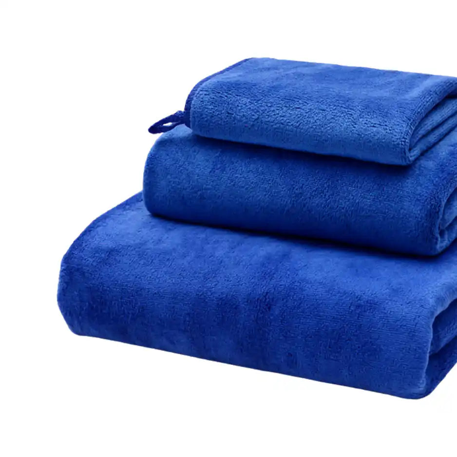Tres toallas azul de microfibra para cuerpo, manos y cara, de la marca Enigma Store, en una imagen con varias toallas dobladas.