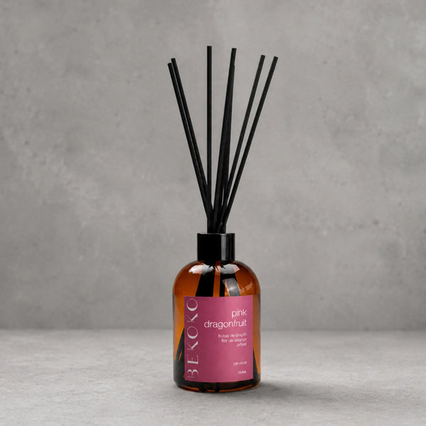 Difusor ambiental BEKOKO con varillas y aroma de dragonfruit y ámbar en frasco de 250ml, en decoración moderna y elegante.